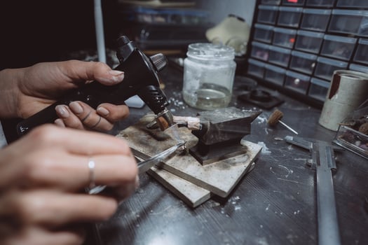 In the workshop, a woman jeweler is busy soldering jewelry photo