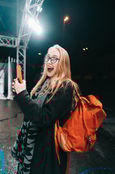Blonde woman with smartphone at night in the street. photo