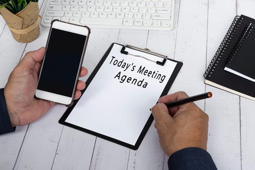 Businessman writing Today's Meeting Agenda with holding a smartphone. photo