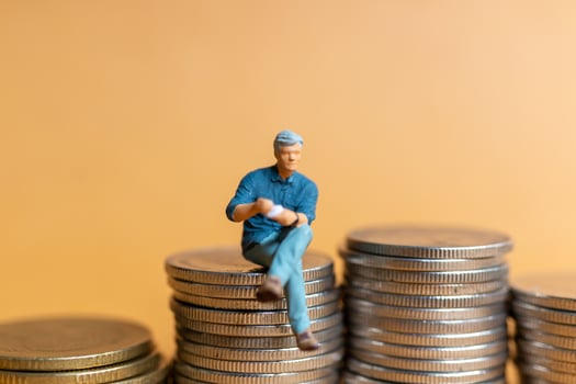 Miniature people, Businessman sitting on coins stack photo