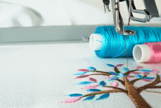 Picture of workspace in the embroidery machine close up look under the needle, lovely tree minimal sytle on background have two colorfull thread cyan and pink. photo