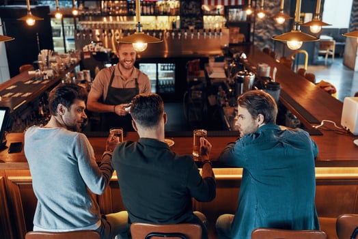 Top view of relaxed young men in casual clothing drinking beer while sitting in the pub photo