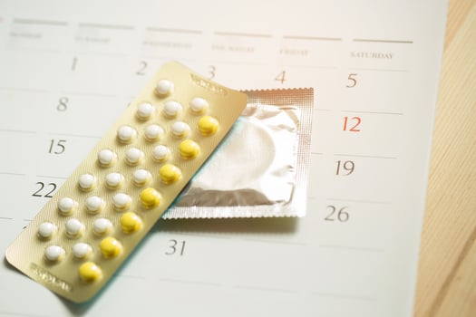 Contraceptive control pills and condom on date of calendar calculate date Control the birth rate. table wood background. health care and medicine, contraception concept. empty space for text. photo