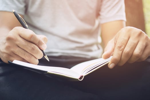 close up hand young woman are sitting on a marble chair. using pen writing Record Lecture note pad into the book in park public. photo