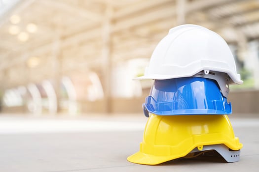 white, yellow and blue hard safety helmet hat for safety project of workman as engineer or worker, on concrete floor photo