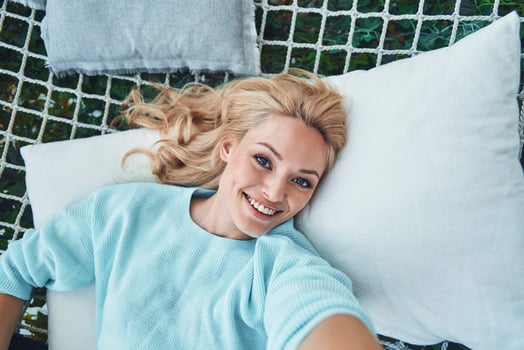 Top view of beautiful young smiling woman making selfie while relaxing in big hammock photo