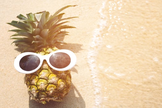 Pineapple with sunglasses sunbathe sunshine on tropical beach with a wave's photo