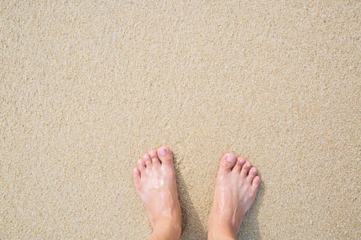 Close Up of a man's bare feet stand at wet on the beach photo