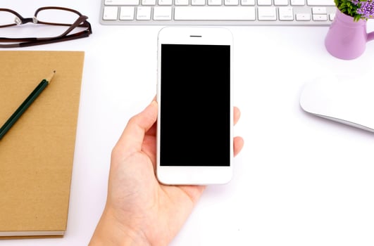 woman hands holding empty screen of smartphone on white desk work. photo