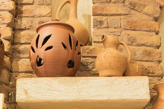 clay jars on a stone shelf in orient room. close up photo