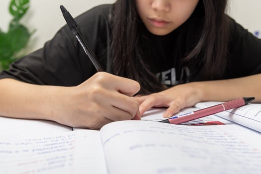 Asian student girl is writing homework and reading book at desk photo