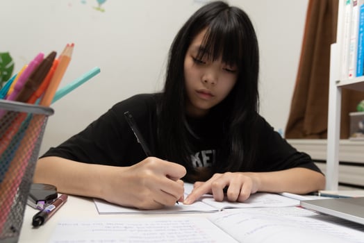 Asian student girl is writing homework and reading book at desk photo