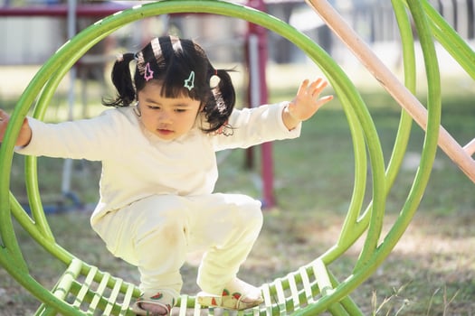 Cute asian girl play on school or kindergarten yard or playground. Healthy summer activity for children. Little asian girl climbing outdoors at playground. Child playing on outdoor playground. photo