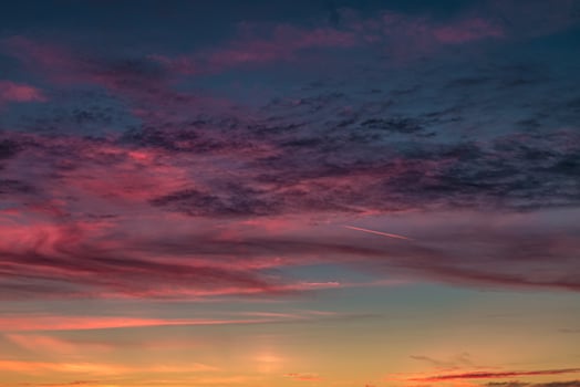 Blue violet red sunset sky background with evening fluffy curly rolling cirrostratus clouds. Good windy weather photo