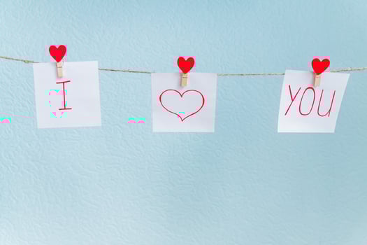 Red Valentine's love hearts pins hanging on natural cord against blue background. I love you inscription on paper pieces. photo