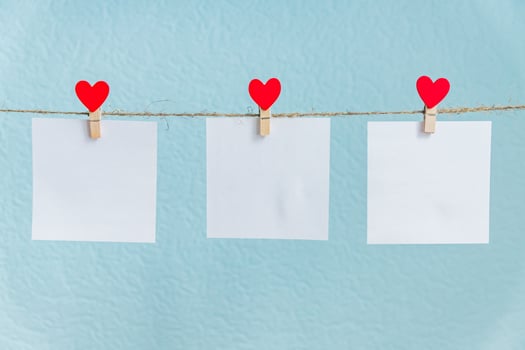 Blank cards on pins with red hearts. Mockup for text and blue background for Valentines Day greetings photo