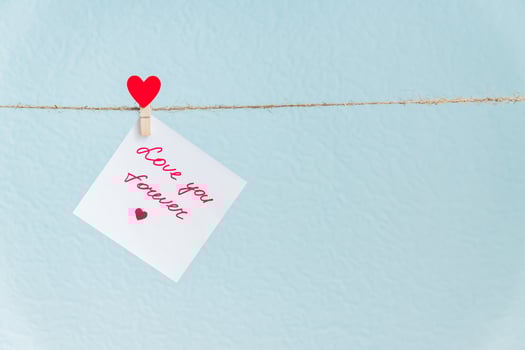 Red Valentine's love hearts pin hanging on natural cord against blue background. drawn heart on paper piece. photo