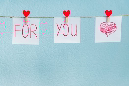 Red Valentine's love hearts pins hanging on natural cord against blue background. love you forever inscription on paper pieces. photo