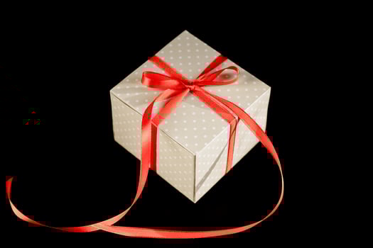 Beige polka dot gift box with red ribbon bow on black background with copy space. photo