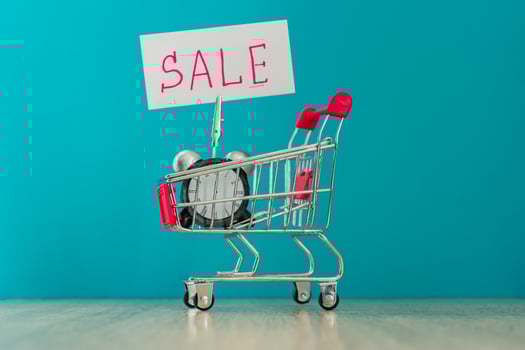 Alarm clock and banner with handwritten world SALE on wooden table. Shopping concept. photo