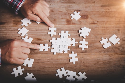 Hands holding jigsaw puzzles piece on wooden table background, success business, solution strategy, teamwork partnership concept photo