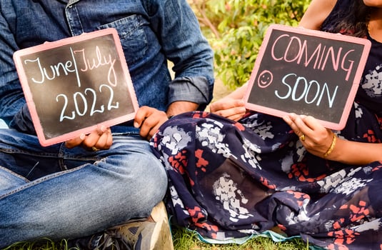 Indian couple posing for maternity baby shoot. The couple is posing in a lawn with green grass and the woman is falunting her baby bump in Lodhi Garden in New Delhi, India photo