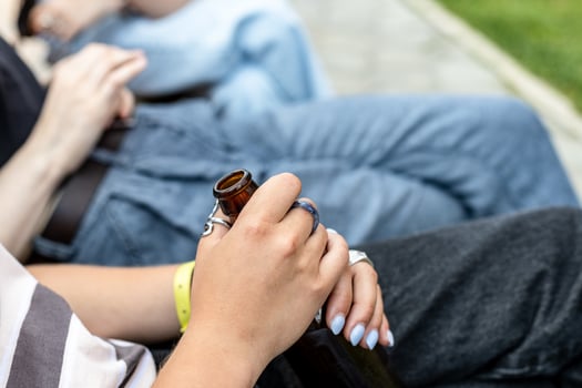 sitting girl holding neck of open glass bottle photo