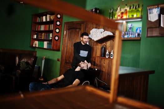 Handsome bearded man at the barbershop, barber at work. Washing head. photo
