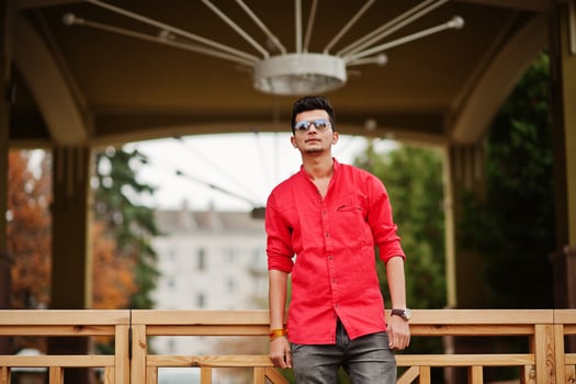 Indian man at red shirt and sunglasses posed outdoor. photo