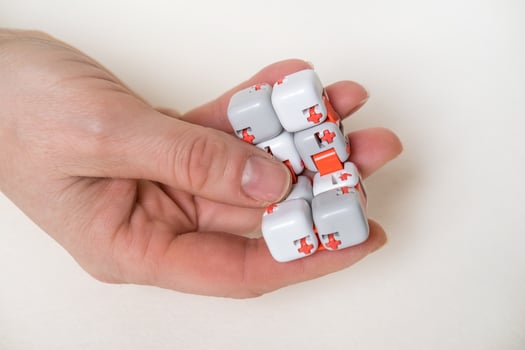 Colorful fingers antistress fidget cube toy in hand on white background. development of fine motor skills of fingers of children photo