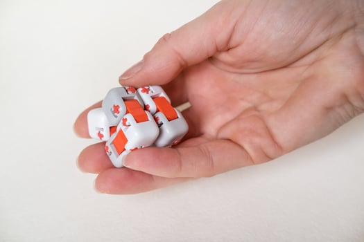 Colorful fingers antistress fidget cube toy in hand on white background. development of fine motor skills of fingers of children photo