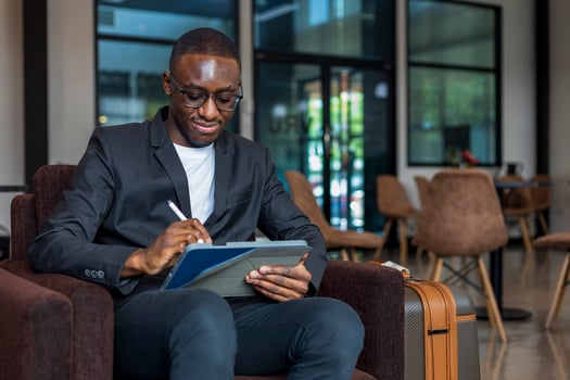 African American businessman is using digital tablet while waiting in airline business departure lounge waiting for boarding the airplane photo