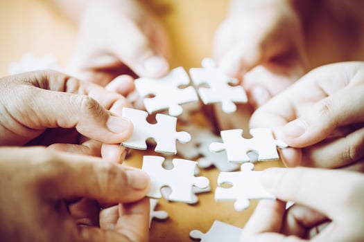 Hands of a person little child and parent playing jigsaw puzzle piece game together on wooden table at home, concept for leisure with family, play with children's development, education and fun. photo