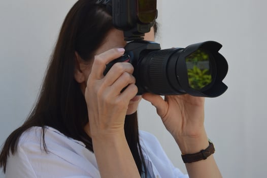 Girl with a camera on a white background. The girl takes pictures on a professional camera. photo