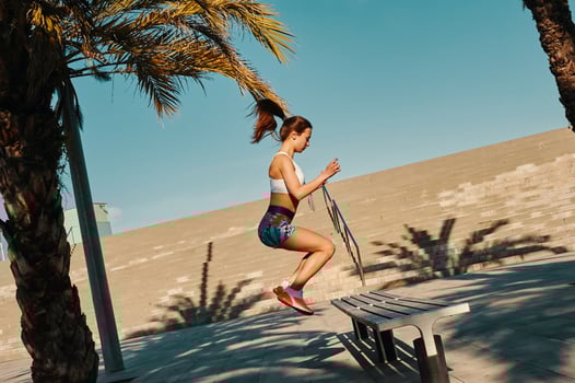 Achieving best results. Full length of beautiful young woman in sports clothing jumping while exercising outdoors photo