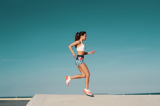 Sport is the way of her life. Full length of beautiful young woman in sports clothing jogging while exercising outdoors photo