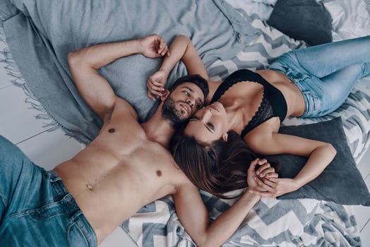 Moments of intimacy. Top view of beautiful young semi-dressed couple lying face to face while spending time in the bedroom photo