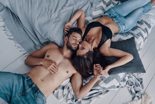 Falling in love. Top view of beautiful young semi-dressed couple lying face to face while spending time in the bedroom photo