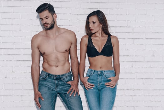 Stylish couple. Beautiful young couple looking away while standing against brick wall photo