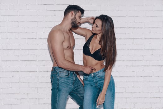 Beautiful young couple looking at each other while standing against brick wall photo