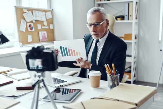 Senior man in elegant business suit showing chart while making social media video photo