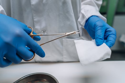 Women's hands in rubber gloves hold a clip and gauze photo