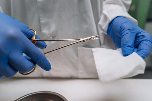Women's hands in rubber gloves hold a clip and gauze photo