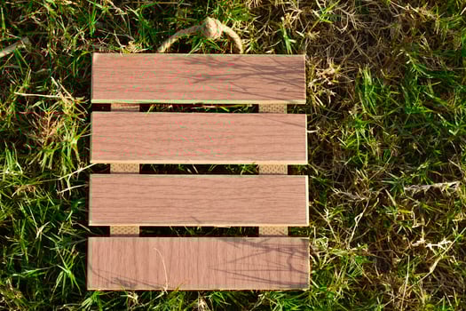 View of empty wooden frame laying on green grass background. Copy space. photo