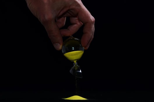 Broken hourglass on black background photo