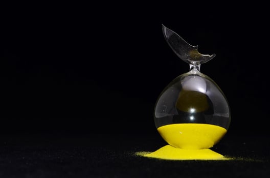 Broken hourglass on black background photo