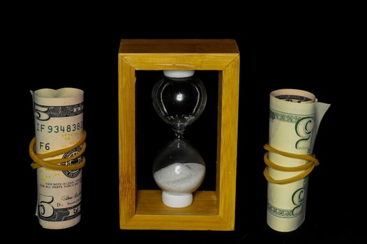 Cash and hourglass on black background photo