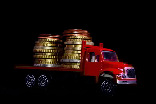 Miniature truck carrying coins on black background photo