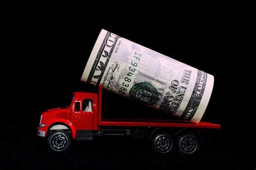 Toy truck with money on black background photo