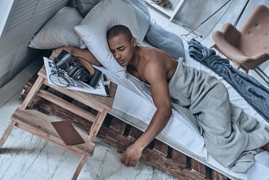 Lost in a deep sleep. Top view of young African man sleeping while lying in the bed at home photo